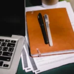 Professional workspace with leather notebook, pens, and laptop for deep studiae learning sessions
