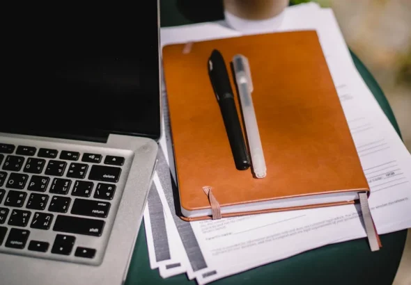 Professional workspace with leather notebook, pens, and laptop for deep studiae learning sessions
